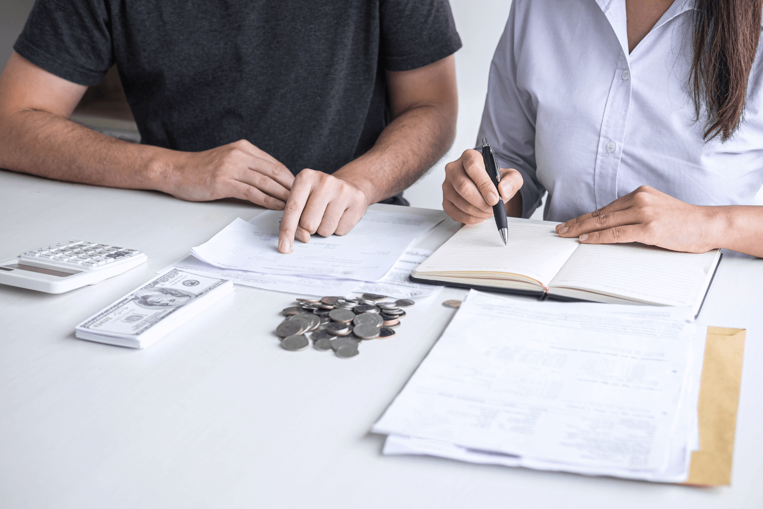 Person using calculator and writing home buying budget on paper