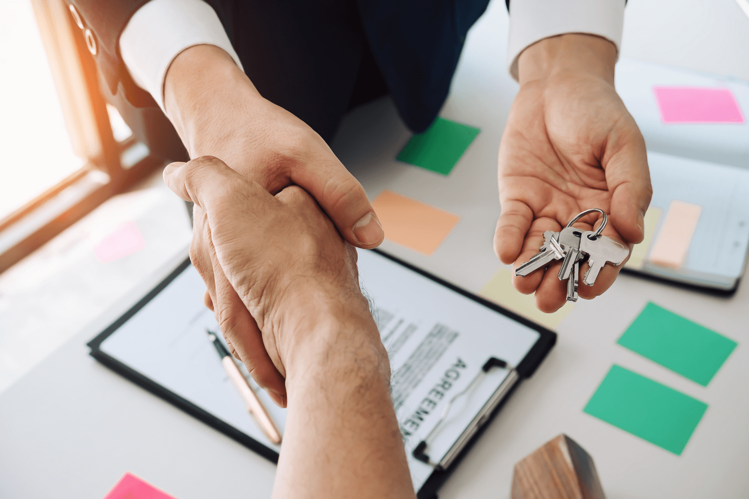 Handshake over home purchase agreement and pen on desk