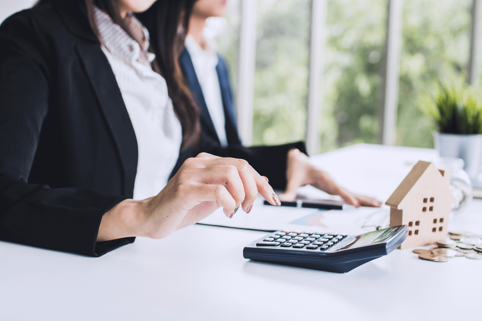 Calculator, house key, and paperwork on a table showing home buying costs