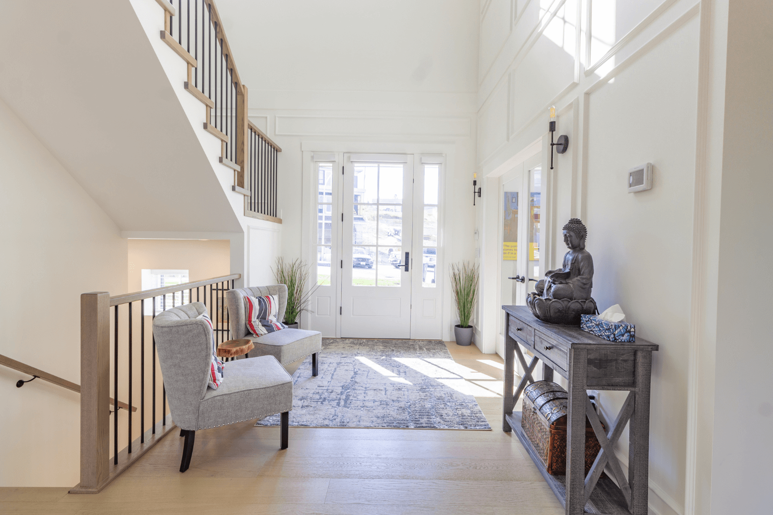 A clean, styled entryway or foyer with a small rug, art, and seating.