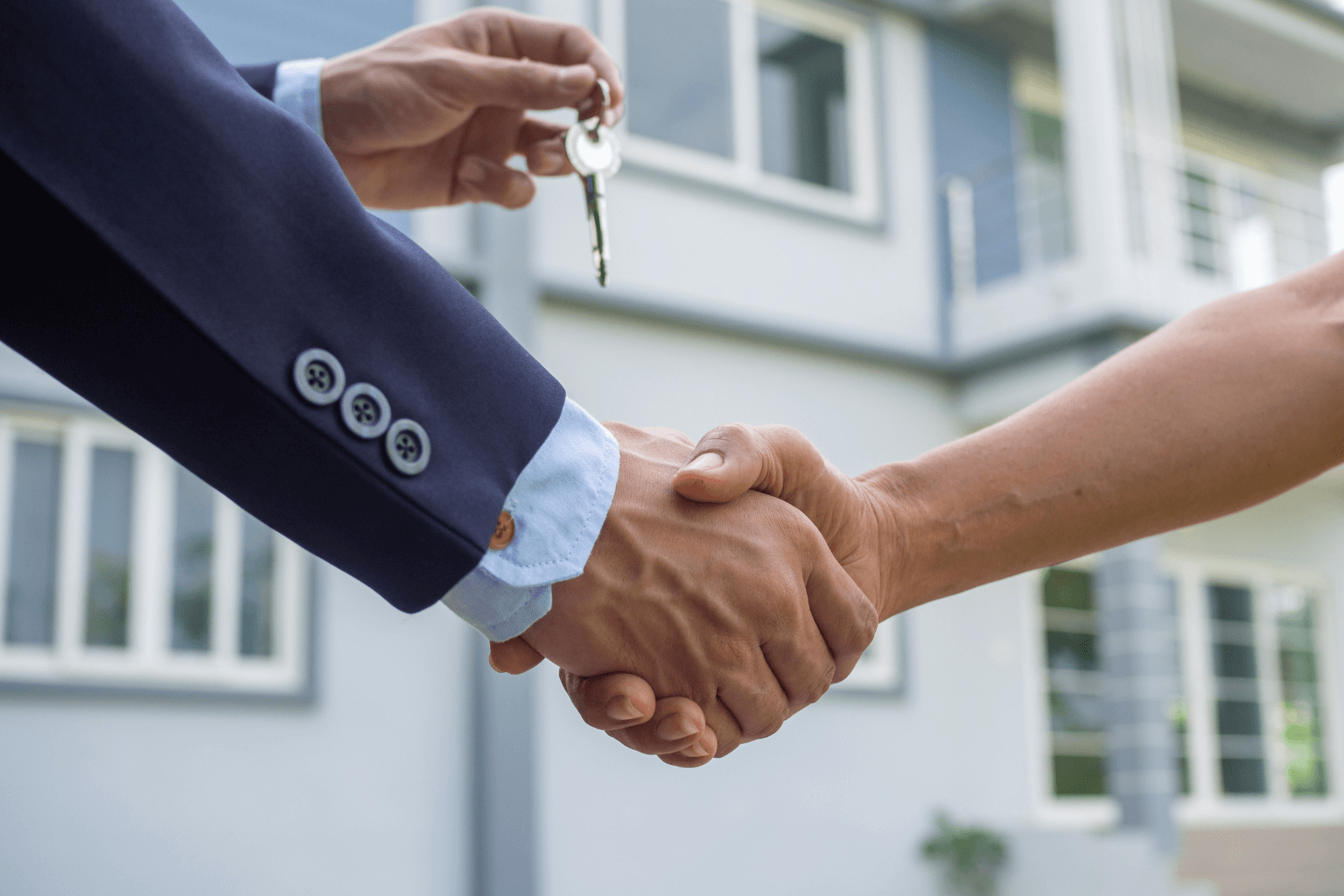 Real estate partners shaking hands in front of a house