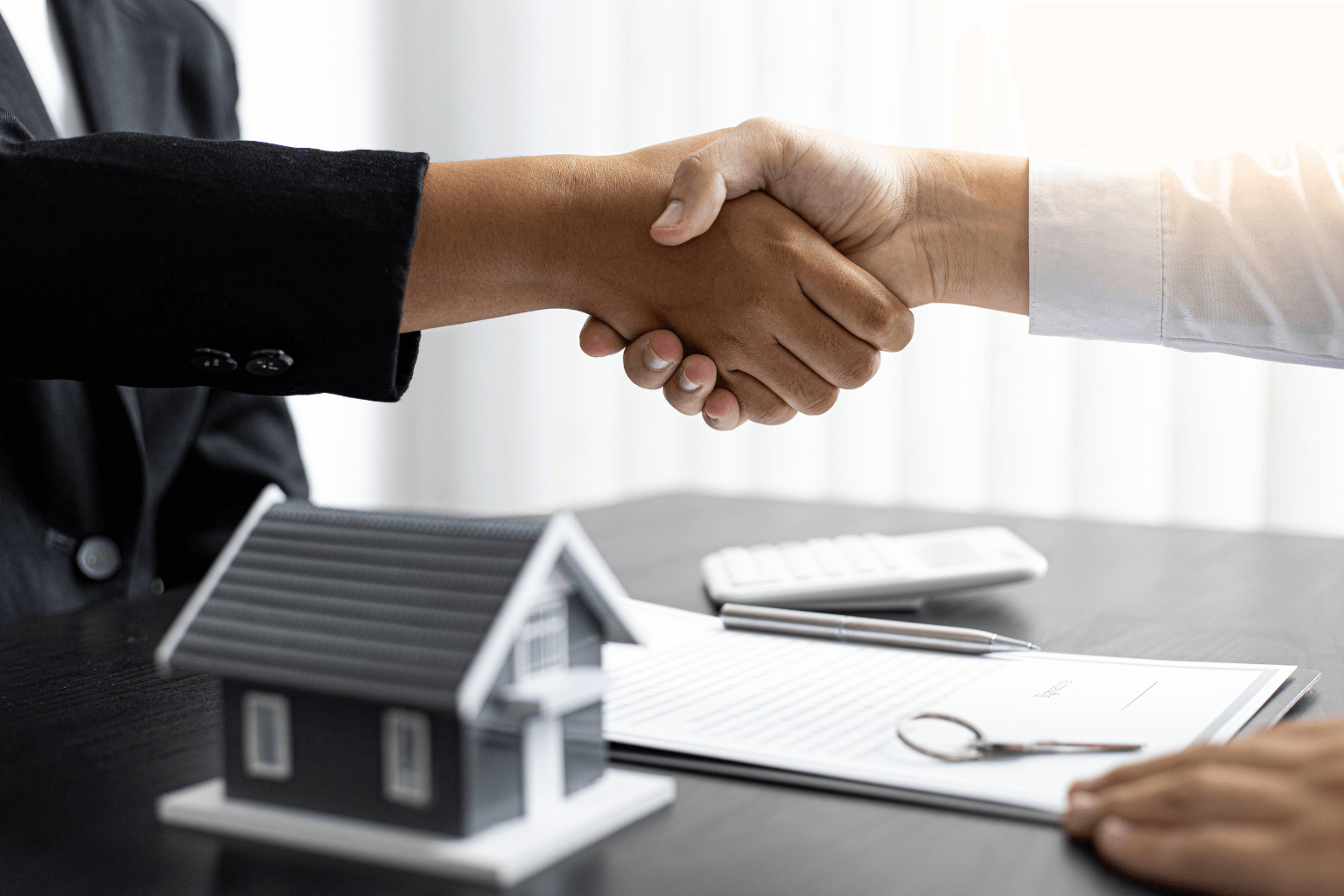 Homebuyer and seller shaking hands over a financing agreement