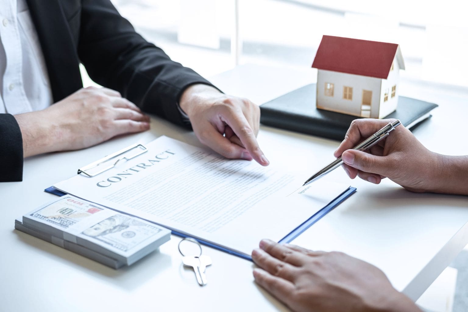 Buyer signing a home purchase contract with a real estate agent
