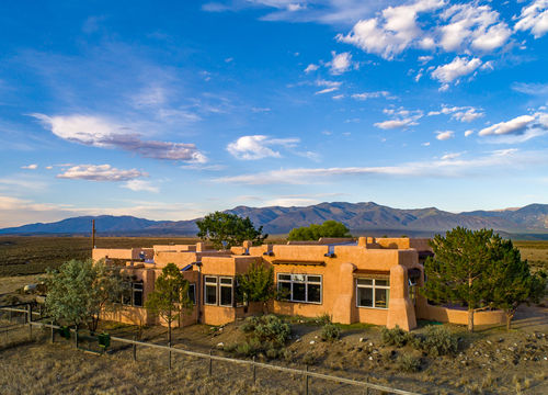 El Prado, NM adobe home with mesa views and Sangre de Cristo Mountains, showcasing Taos County real estate and Southwestern architecture.