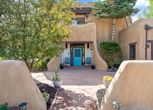 Town of Taos adobe home with blue door and Southwestern architecture near Historic Taos Plaza, showcasing Taos real estate charm.