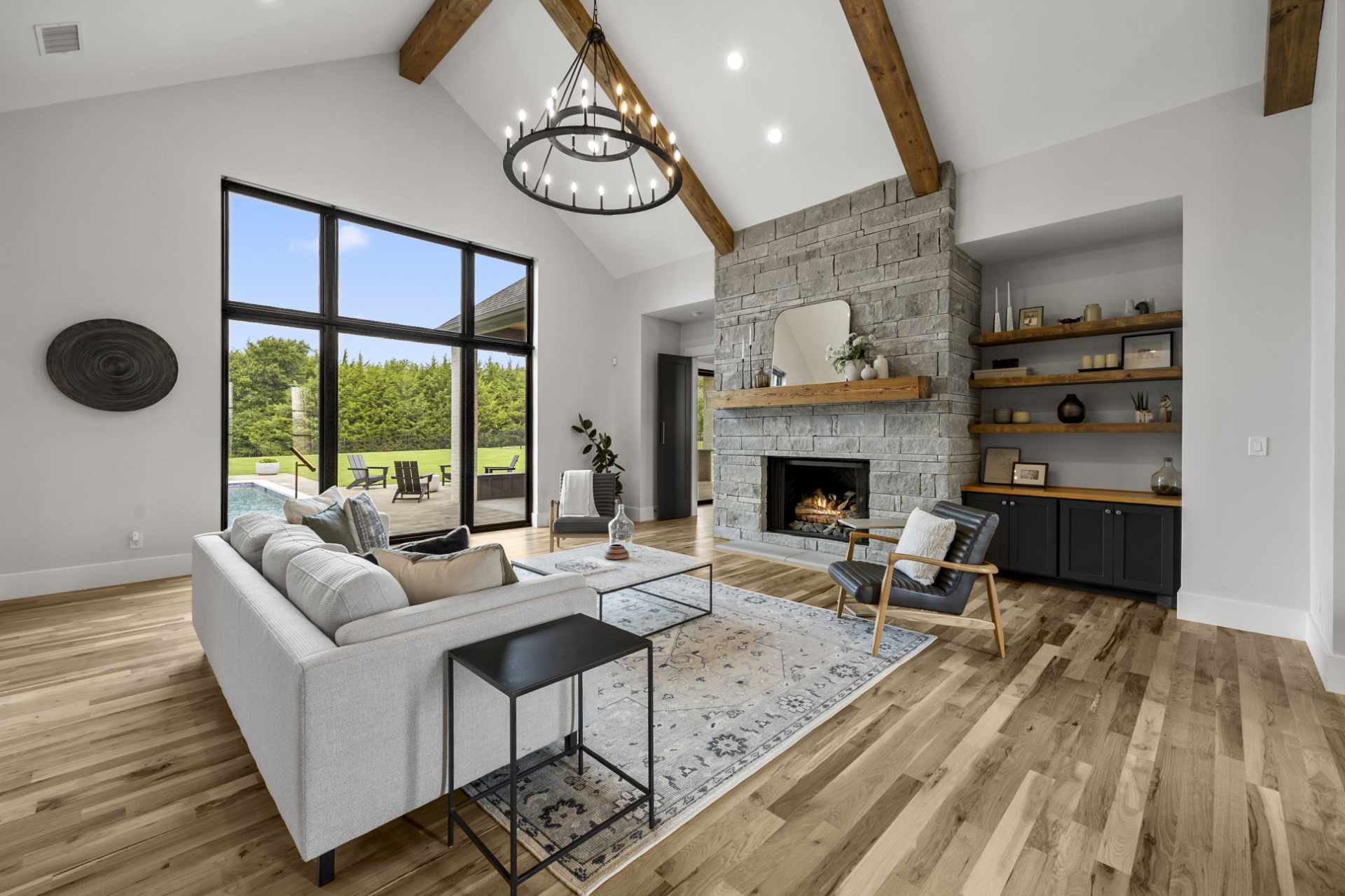 Luxury living room in Rockwall Texas home with stone fireplace, vaulted ceilings, and pool view