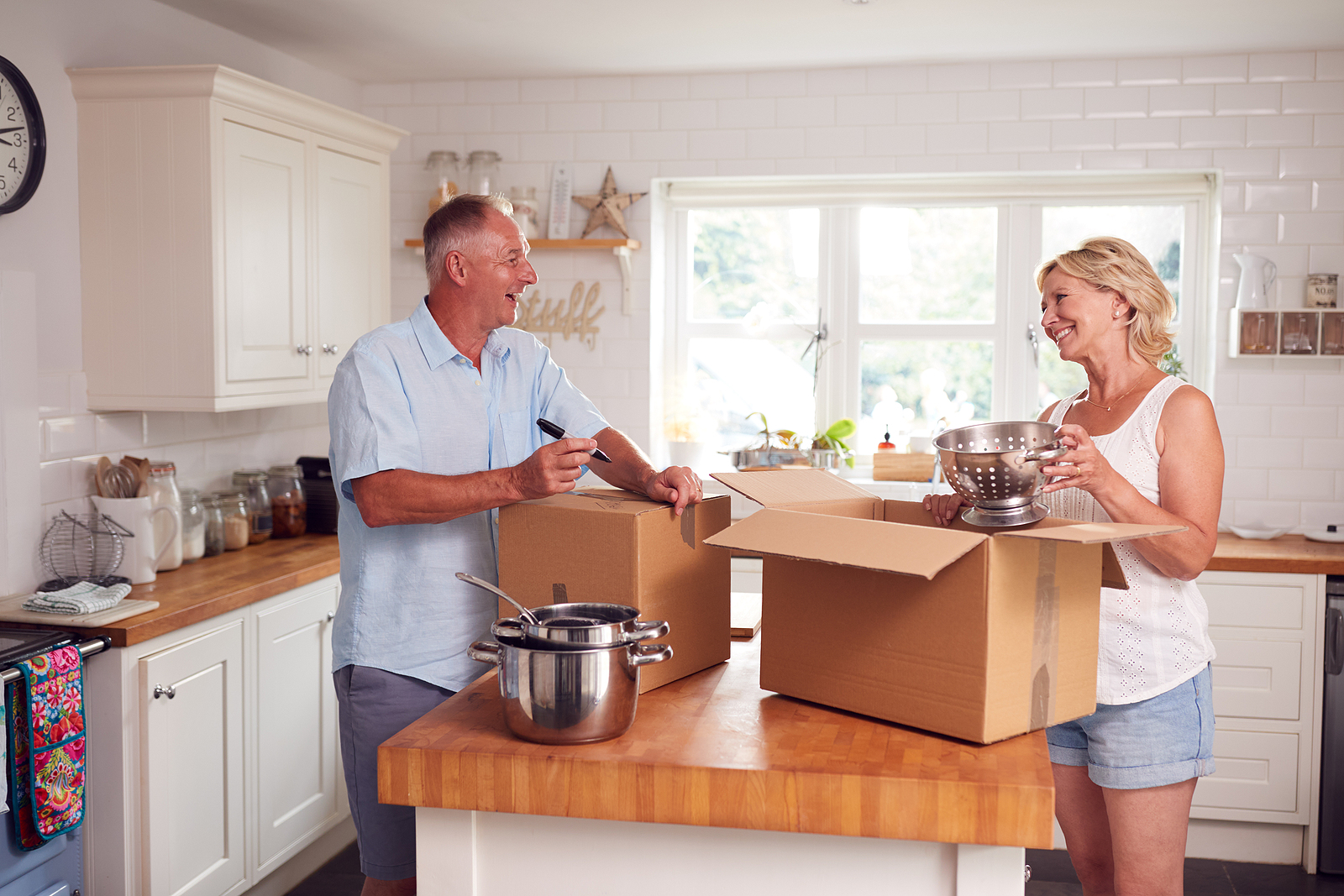 Senior Couple Downsizing In Retirement Packing And Labelling Box