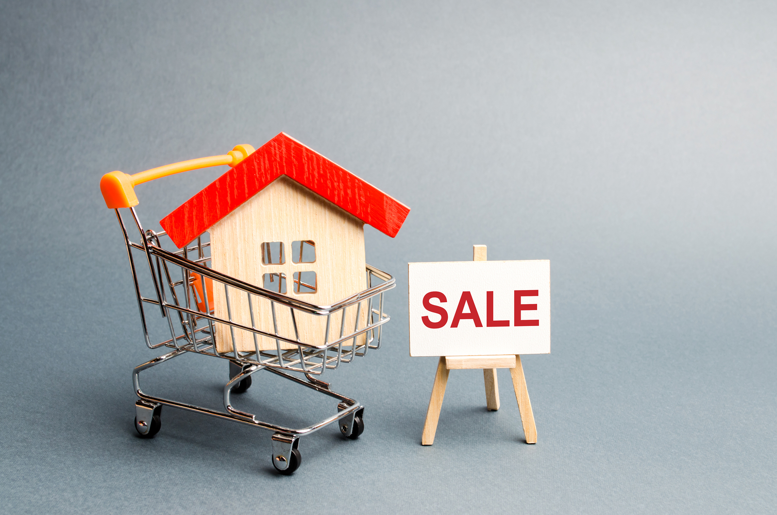 Supermarket Cart With Houses And A Sale Poster. The Concept Of S