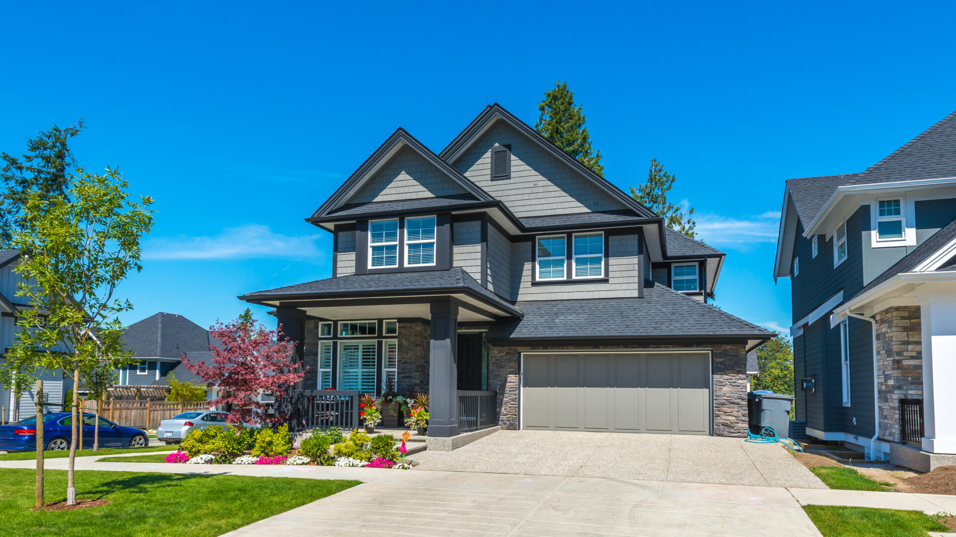 Big custom made luxury house with nicely landscaped front yard and driveway to the garage.