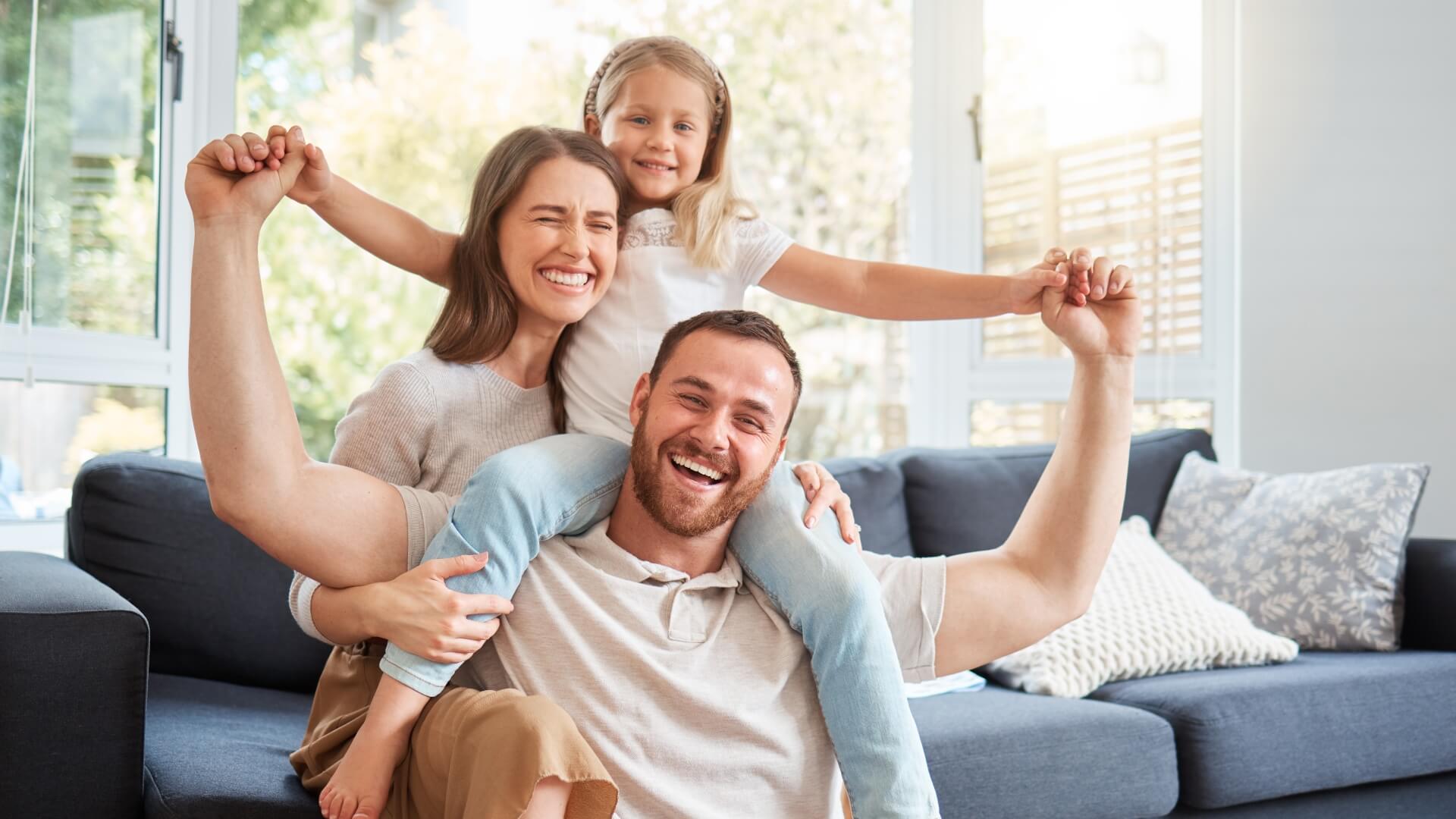 Smile, family and portrait on shoulder by sofa for weekend fun, happiness and bonding together. Playful, mom and dad with daughter in living room