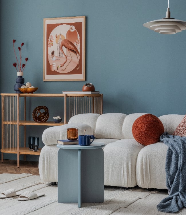 Cozy boucle sofa against a deep blue wall, styled with burnt orange and amber(1)