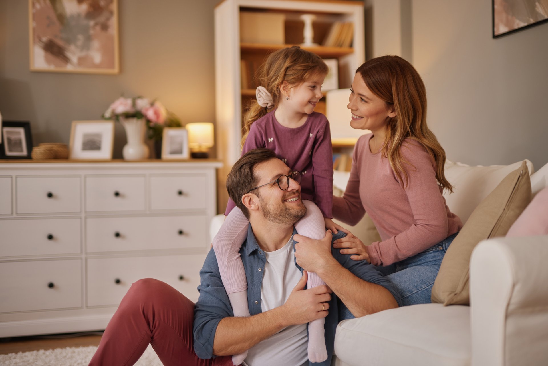 Happy family with little daughter sitting on sofa