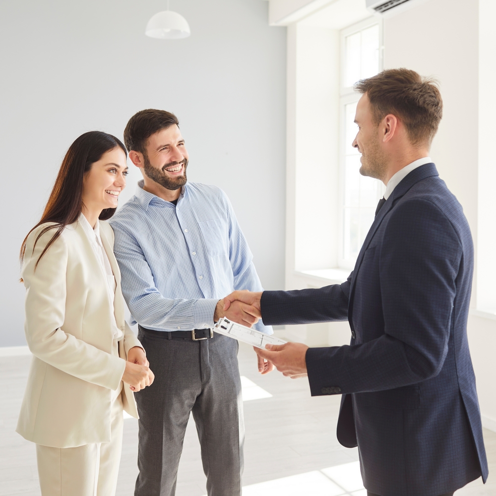 Family,Couple,Shakes,Hands,With,A,Real,Estate,Agent,Or