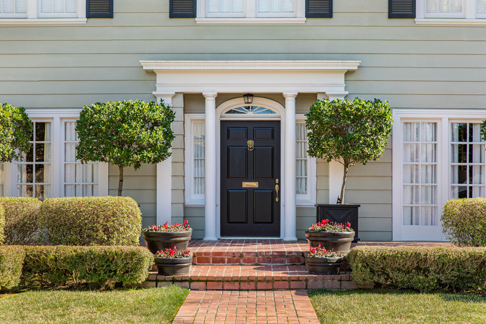 Front door of classic home with landscaped front yard and brick path