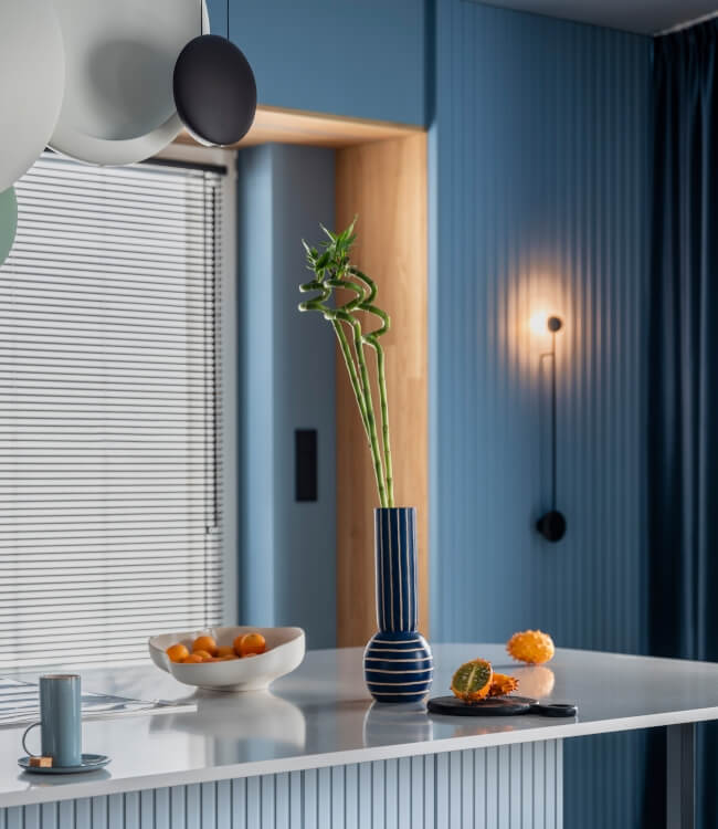 Interior design of kitchen interior with marble kitchen island, blue wall, black chokers