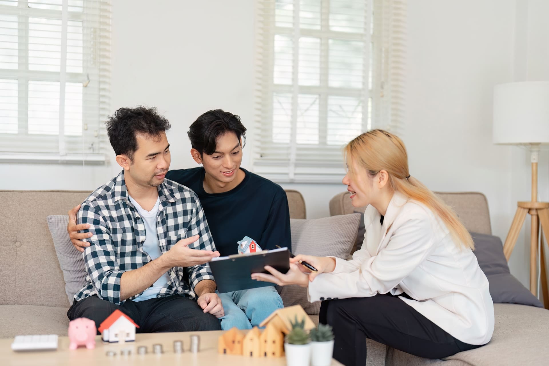 Diverse LGBTQ couple consulting with a real estate agent about home buying.