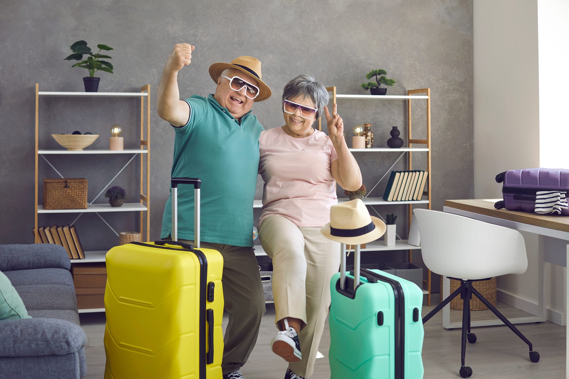 Let's rock this summer. Active senior couple having fun at home before going on holiday trip. Portrait of happy aged husband and wife with packed travel suitcases ready for cool vacation togethe