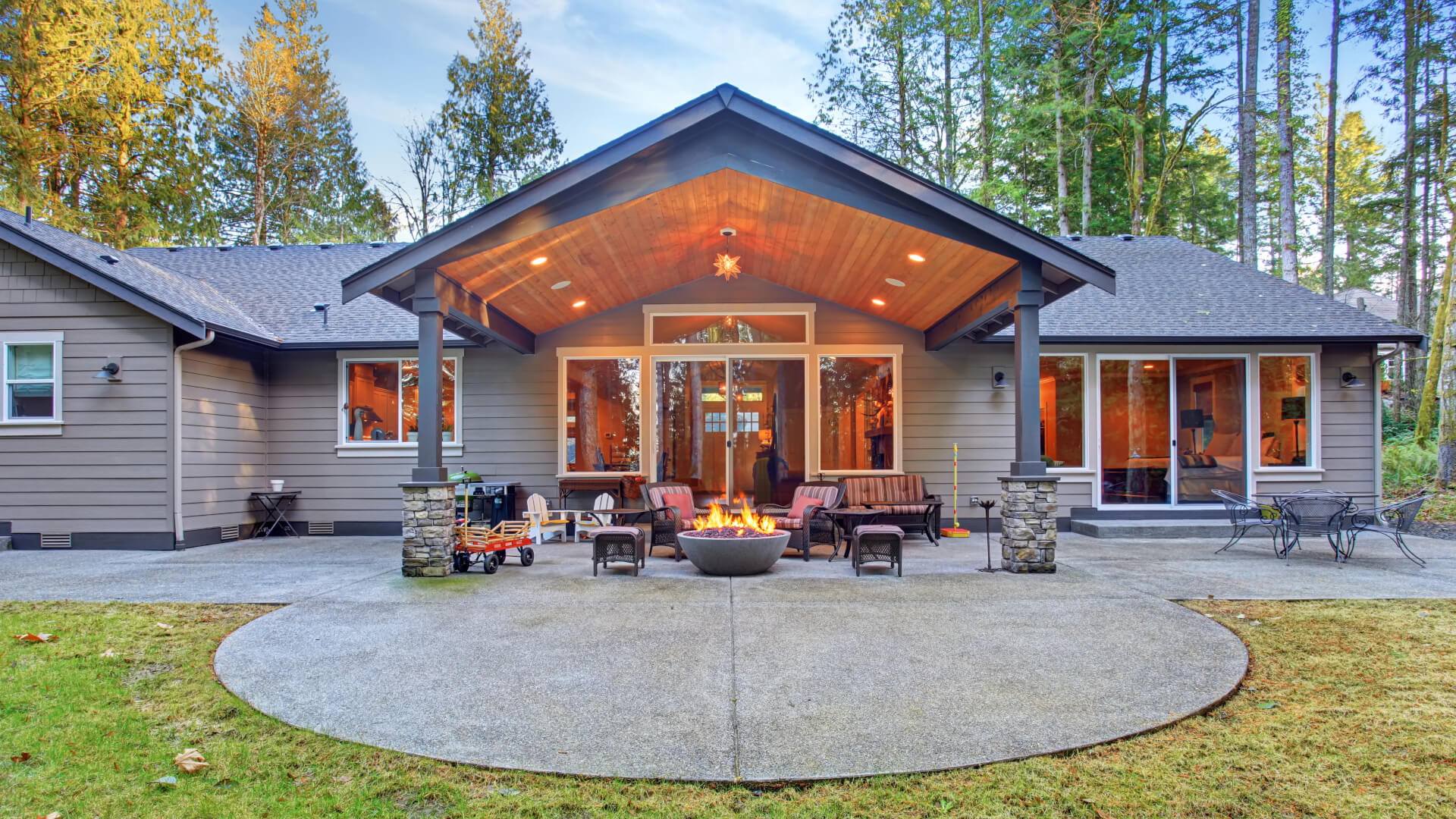 Large back yard with grass and covered patio with fire pit.