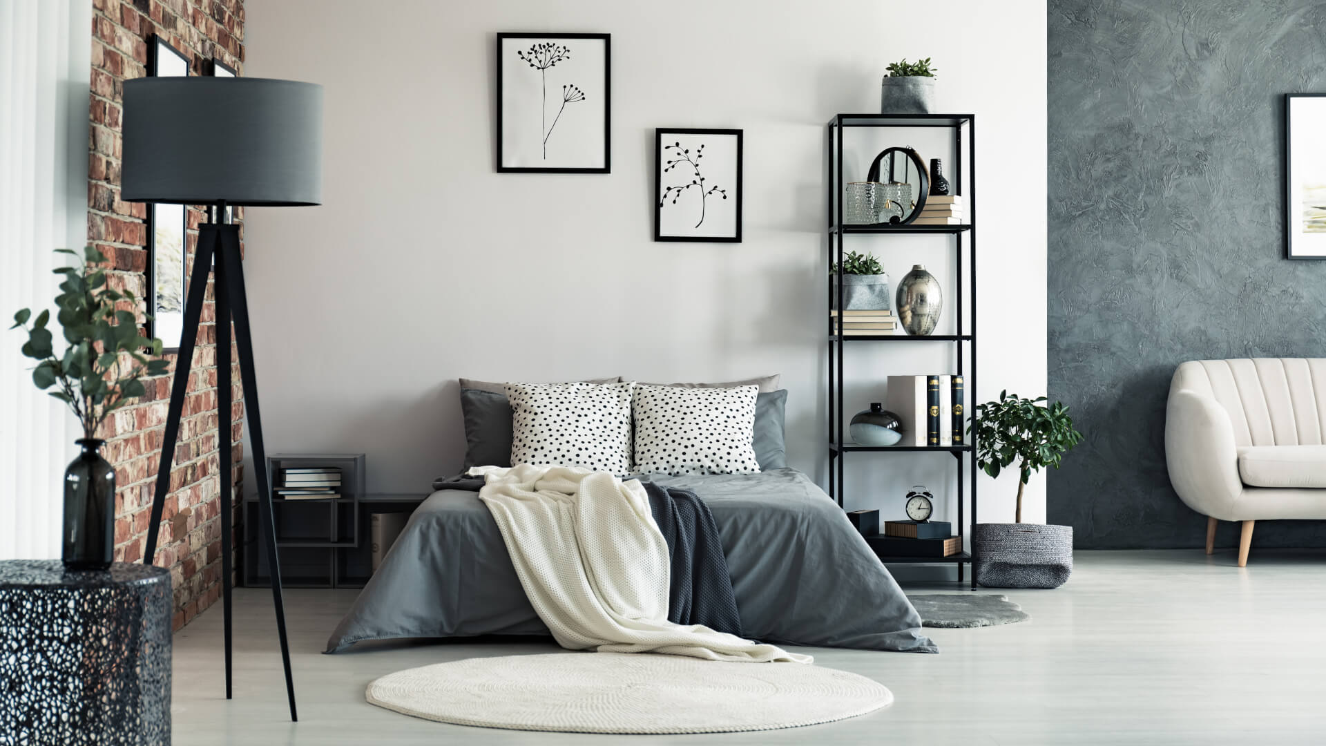 Vase on metal table and grey lamp in spacious bedroom with white carpet and gallery on wall above bed