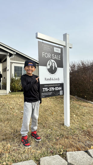 A child Standing Next to a For Sale Sign
