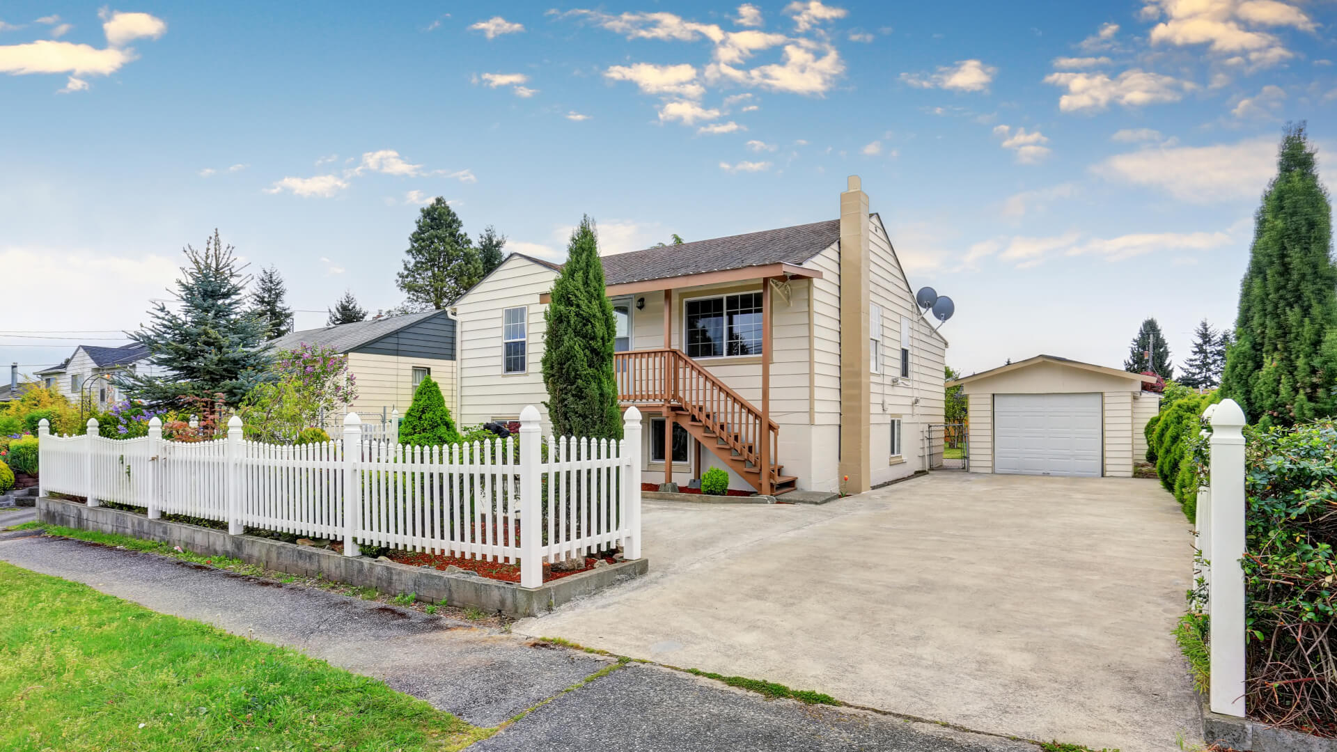 Exterior of American bungalow style house with garage space and concrete driveway.