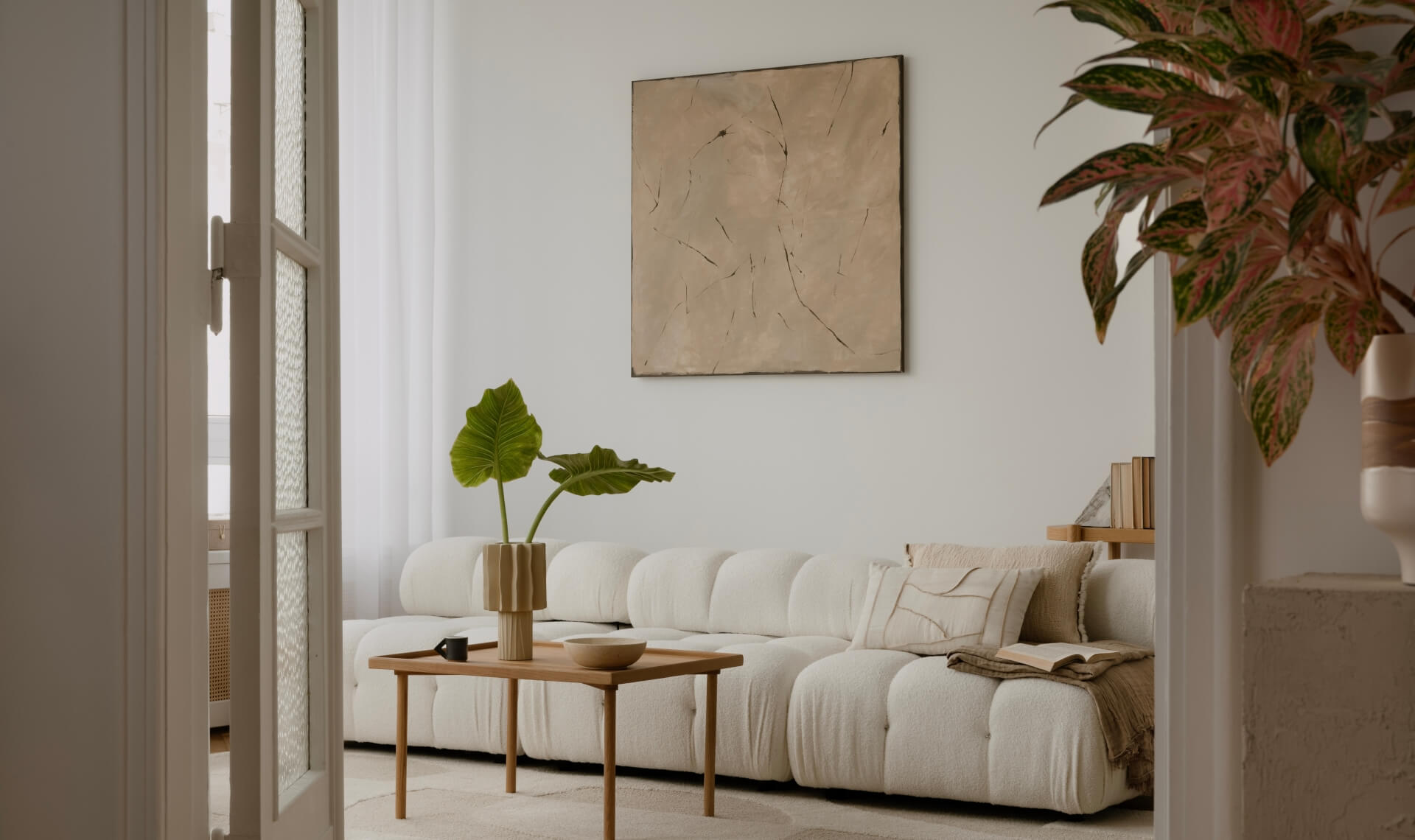 Cosy and stylish interior design of living room with modular white sofa, wooden furnitures, paintings on the wall, decorations, beige