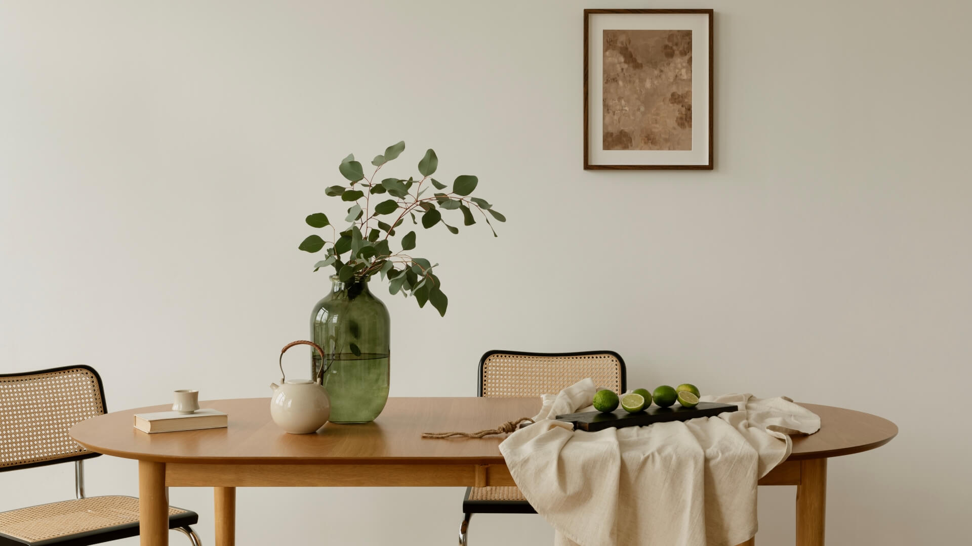 Bright interior with minimalist setup, table styled with greenery, teapot, and limes