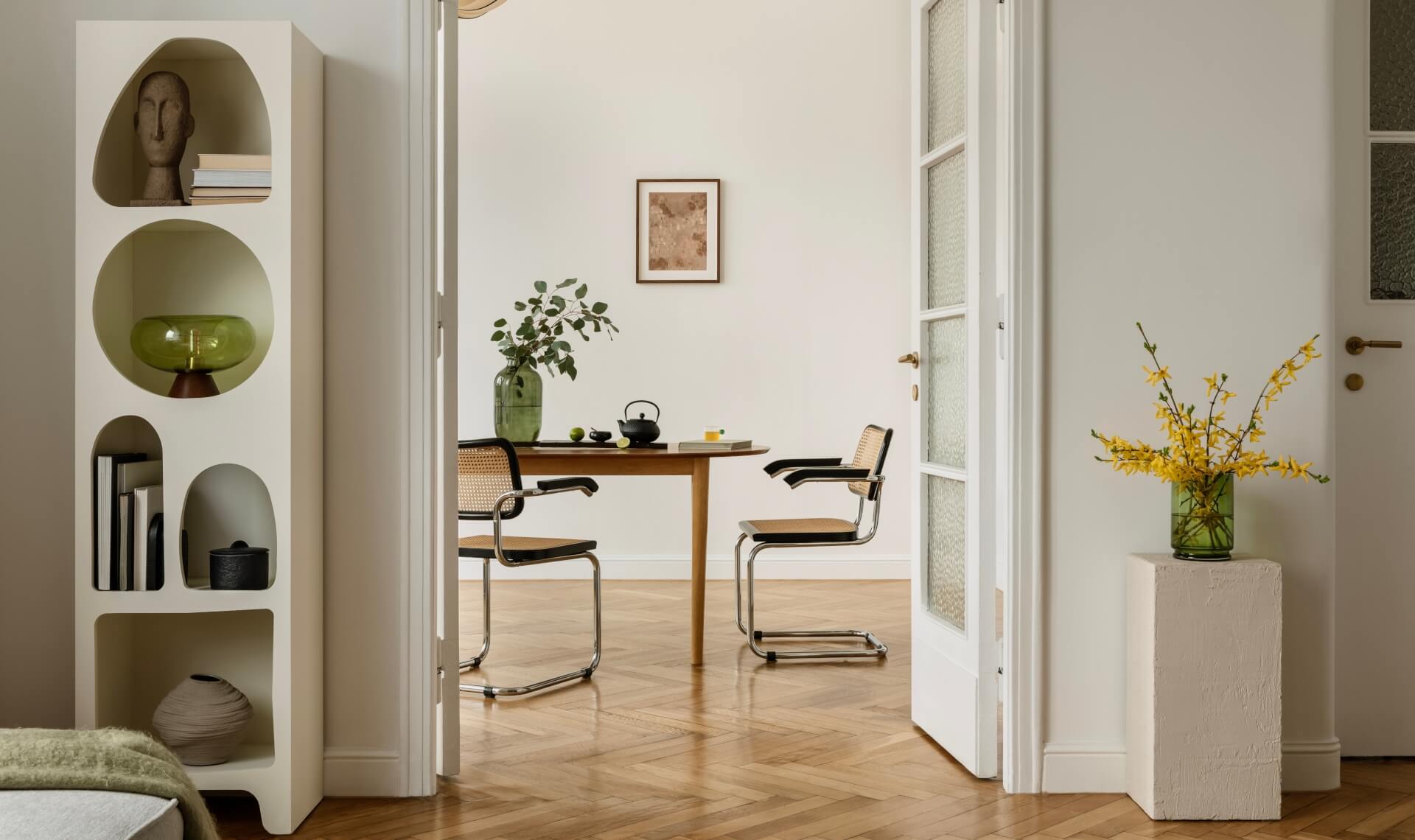 Minimalist dining room, modern chairs, wooden table, green vase with yellow flowers.