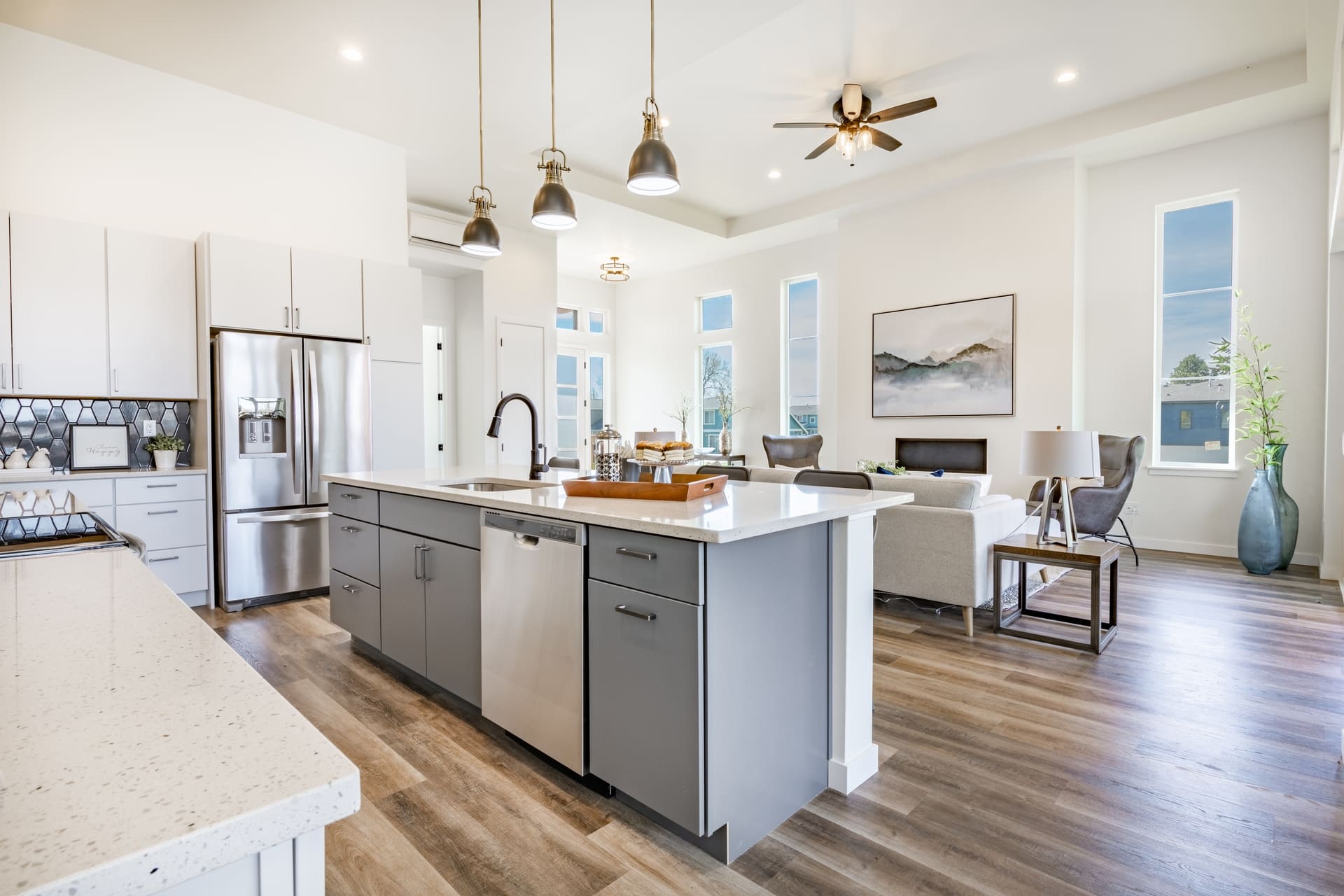 large working chefs kitchen with long white granite counter top hardwood floors grey cabinets stainless appliances large view windows dining table set for dinner