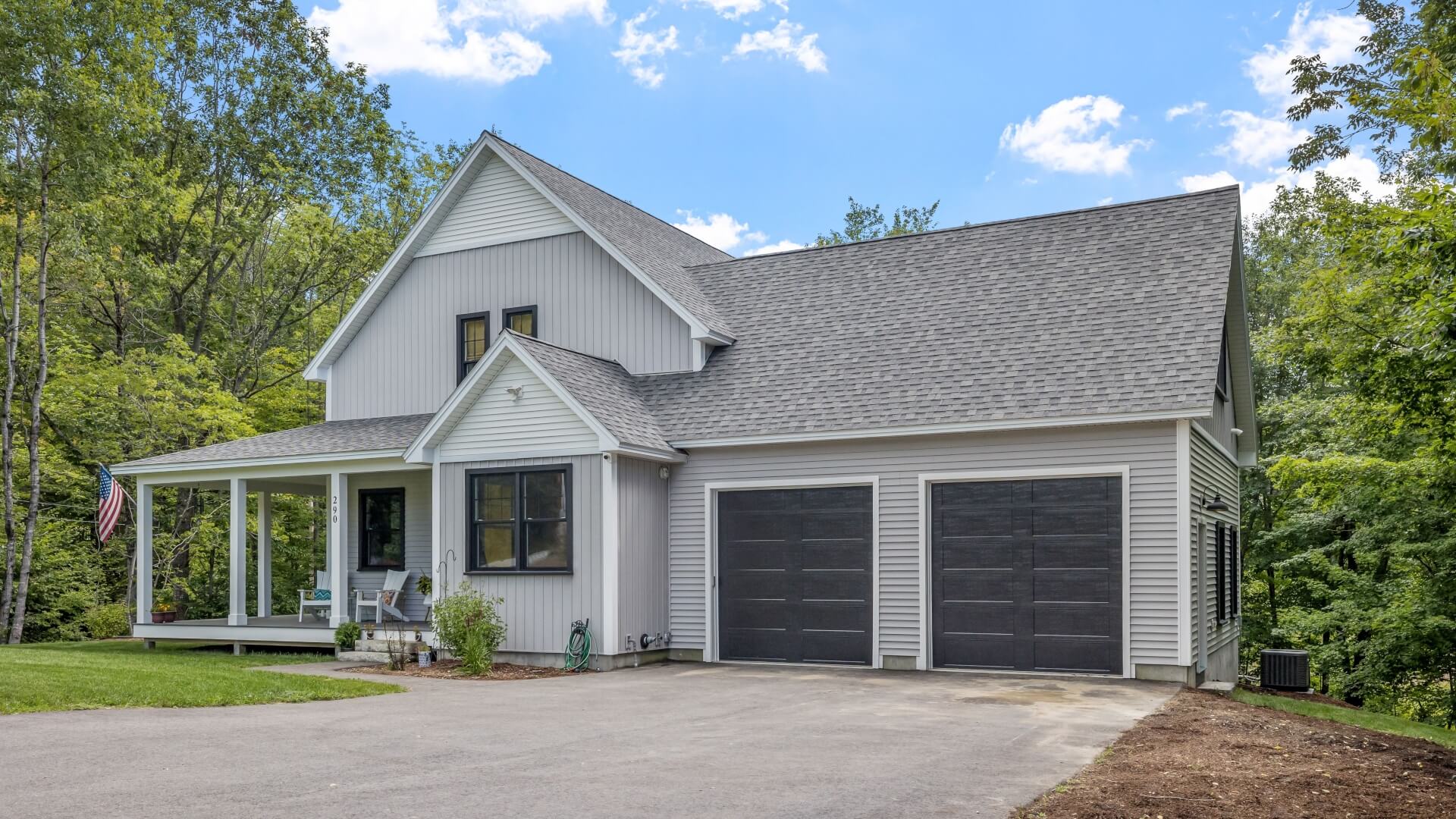 A modern custom new England colonial home with an American flag on a sunny day