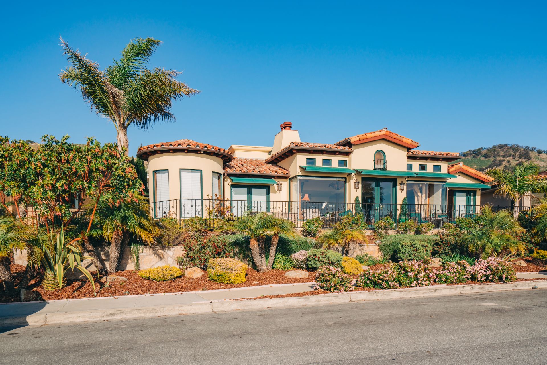 Beautiful houses with nicely landscaped front the yard and clear blue sky on background in a small beach town in California.