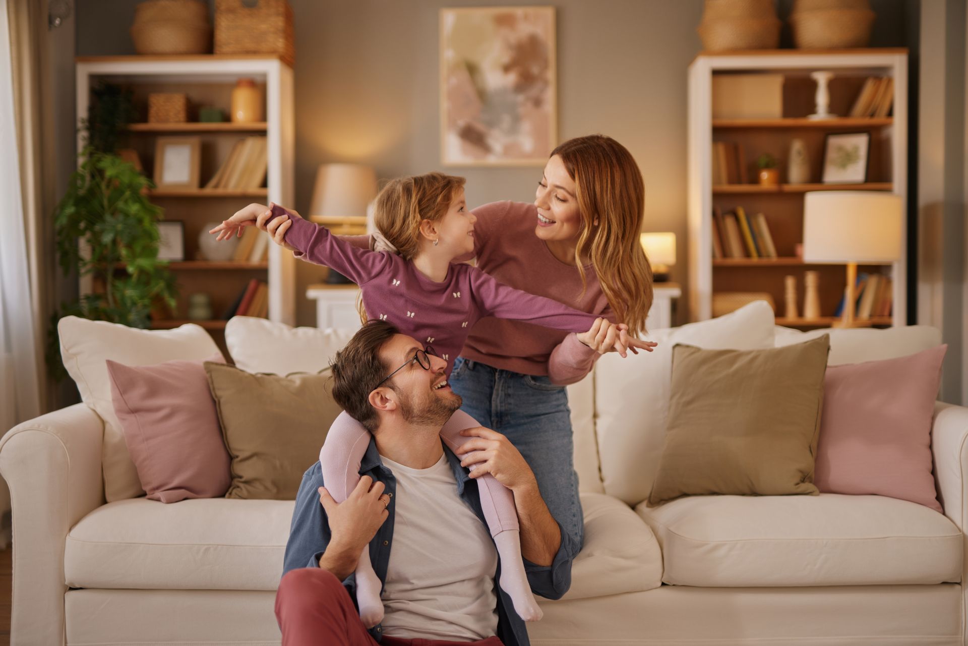 Mom, dad and little daughter playing flying game in the living room (1)