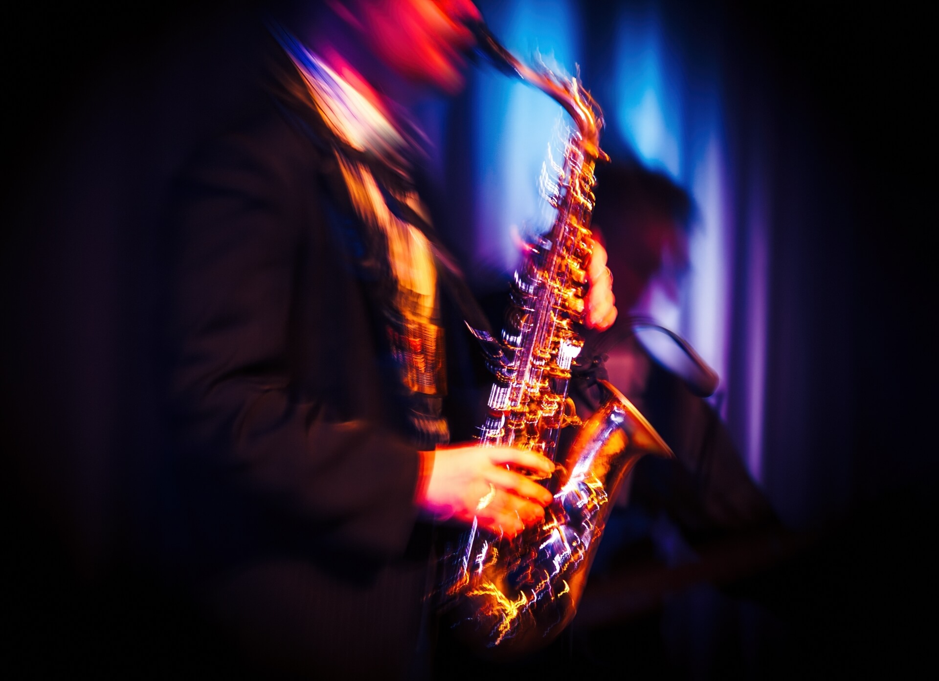 Abstract motion blurred image of a jazz saxaphonist improvising on stage. Jazz music concept.