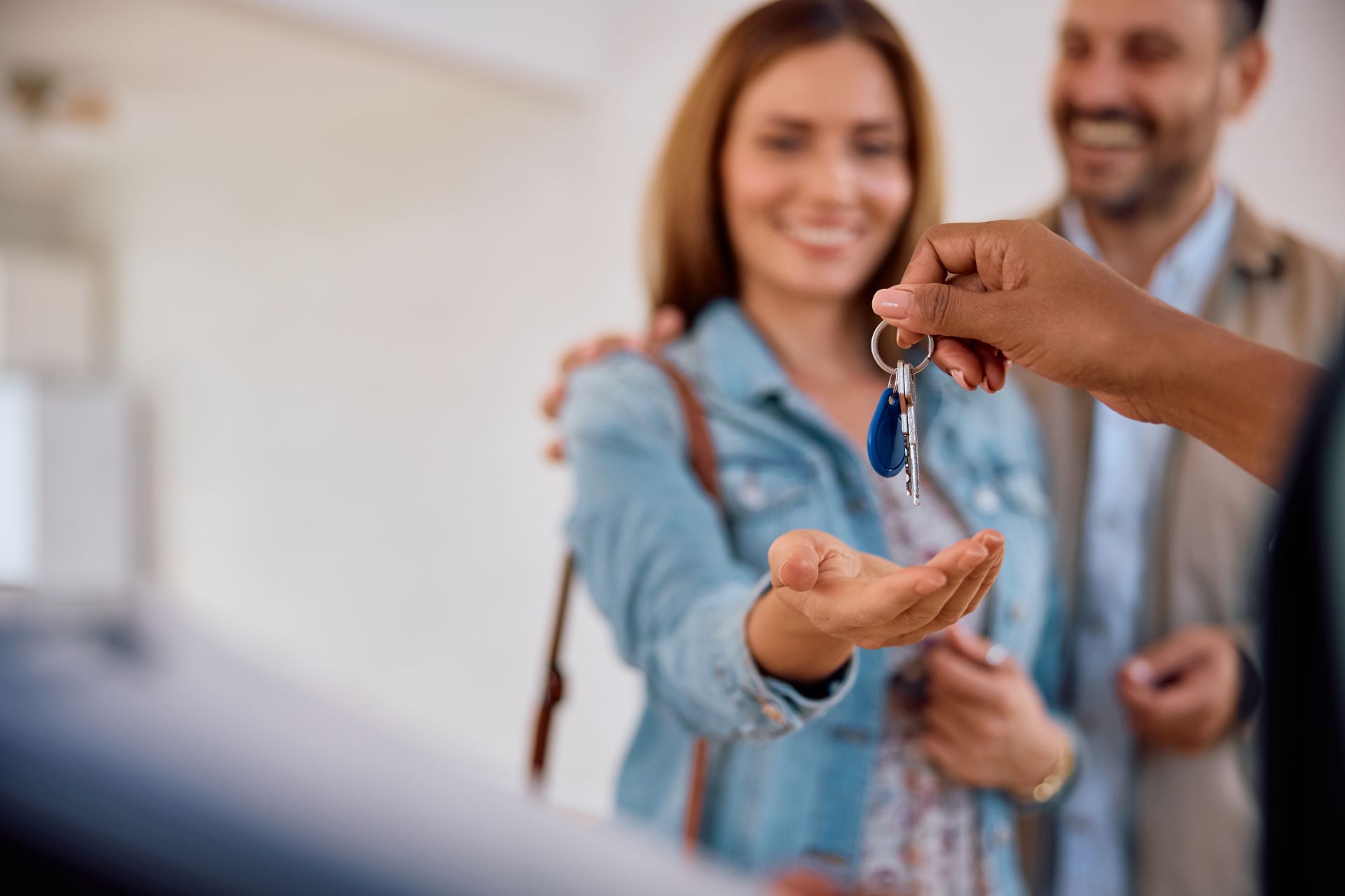 Close up of real estate agent giving new house keys to a couple. Copy space.