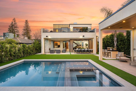 Modern luxury home with a swimming pool and outdoor seating area at sunset.