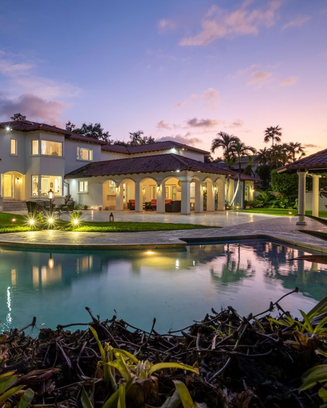 Florida, USA. January Backyard of a modern house with swimming pool, artificial grass, stone path, trees, chairs and an umbrella. vertical