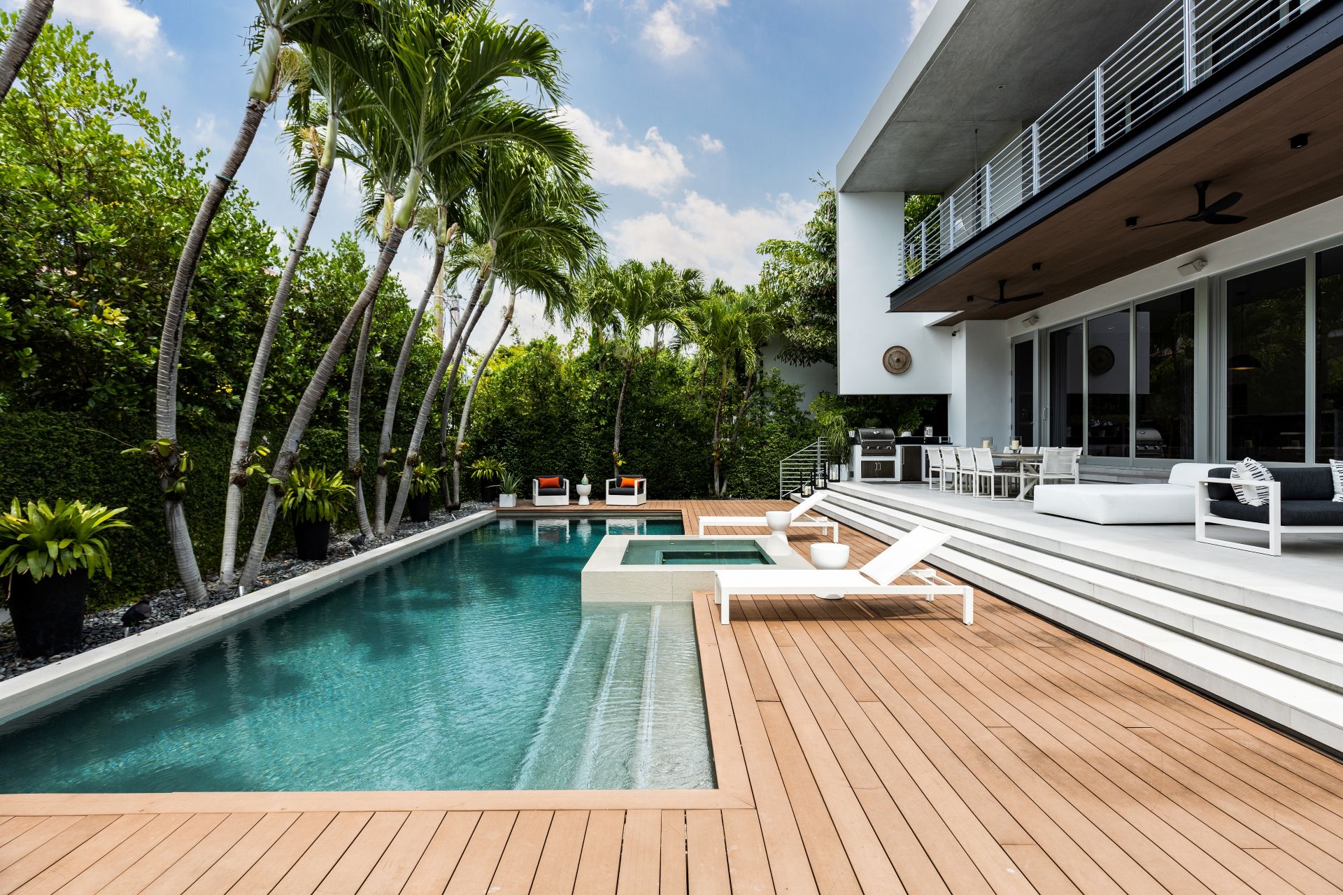 Florida, USA. September Backyard of a modern house with swimming pool, artificial grass, stone path, trees, chairs and an umbrella.