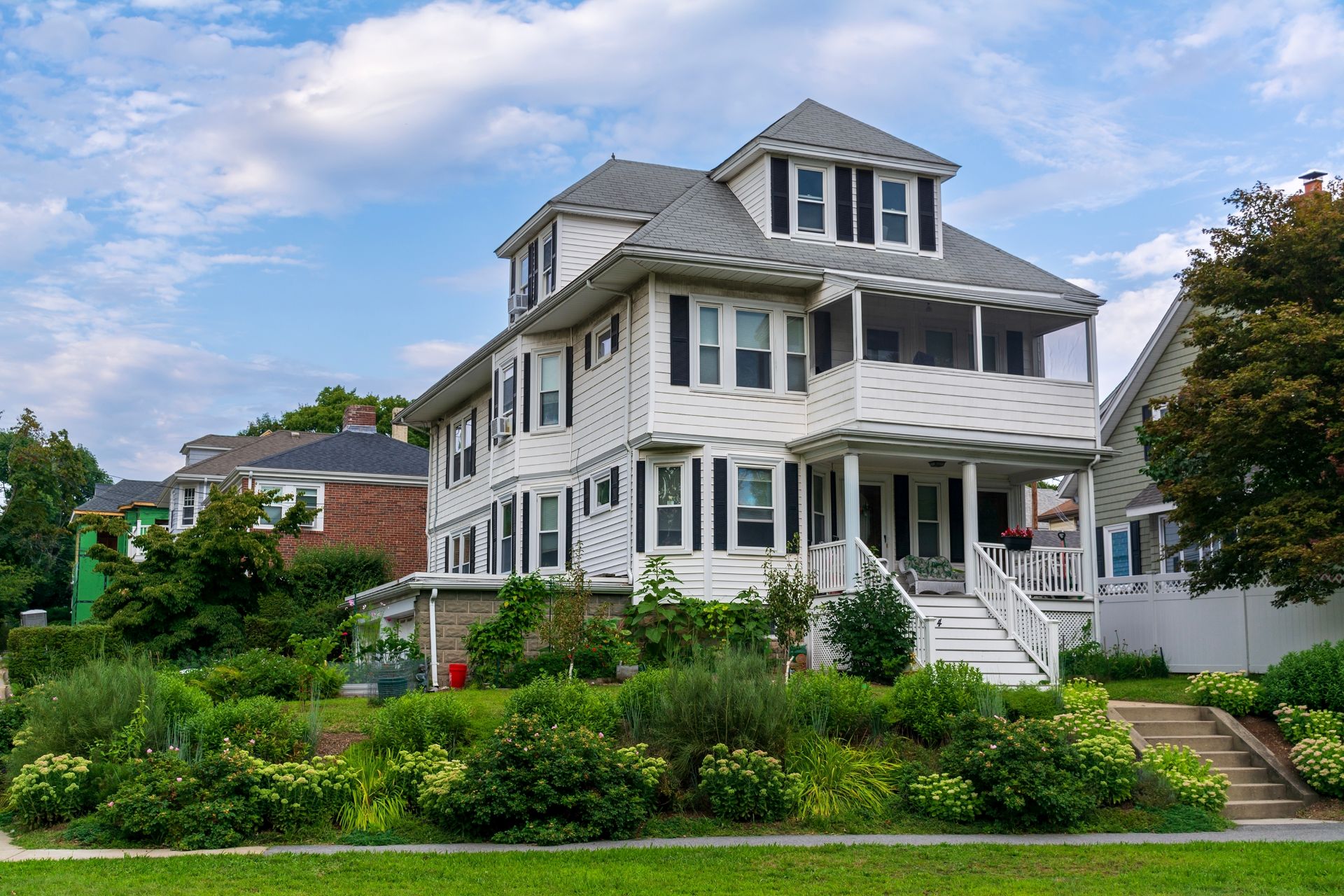 Classic hipped roof house with white siding and black shutters in Watertown, Massachusetts, USA