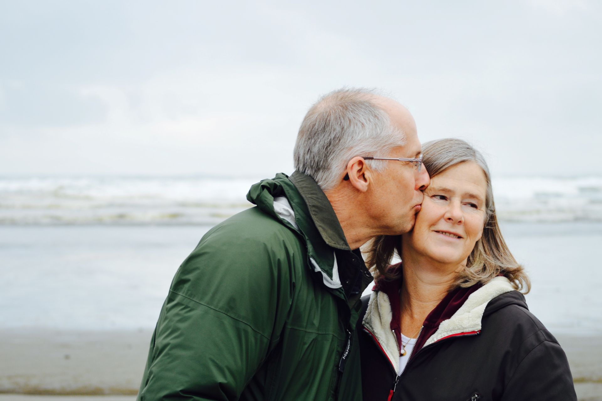 couple with man kissing woman water in the background