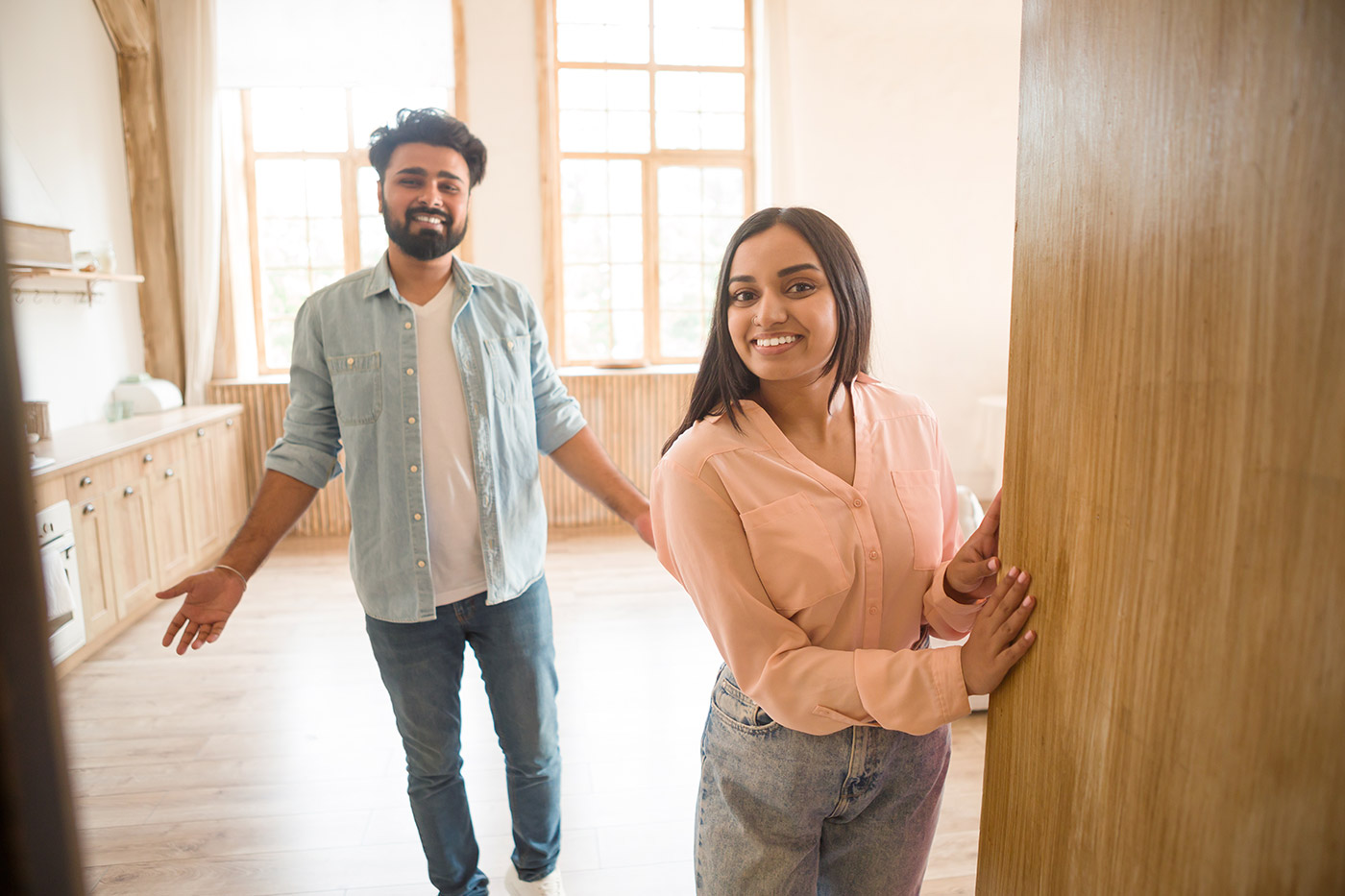 Couple standing in bright empty home during relocation move in moment