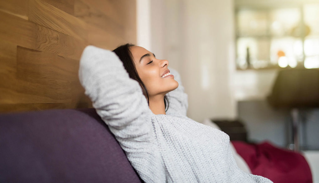 Happy-Woman-Sitting-On-Couch-Peacefully