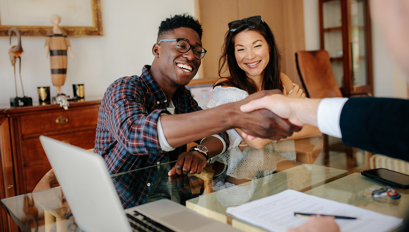 Man-Shaking-Hands-with-Agent-with-Wife-Smiling-1400px