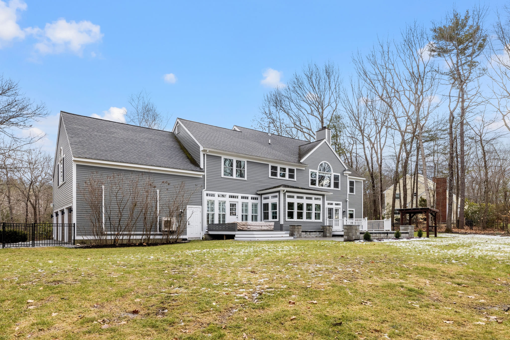 A low angle view of a private house with a gray exterior and a garden out front on a sunny day
