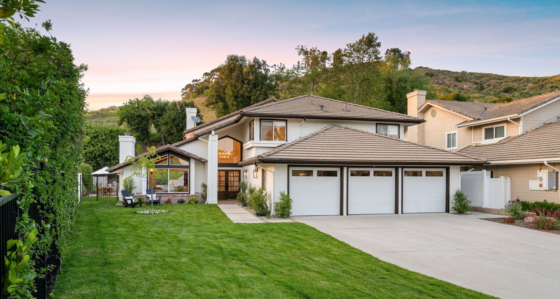 Beautiful suburban house with a well-maintained lawn and a three-car garage at sunset. (1)