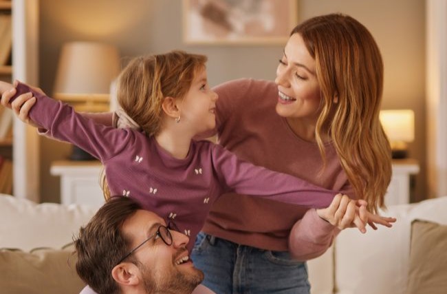 Mom, dad and little daughter playing flying game in the living room (2)