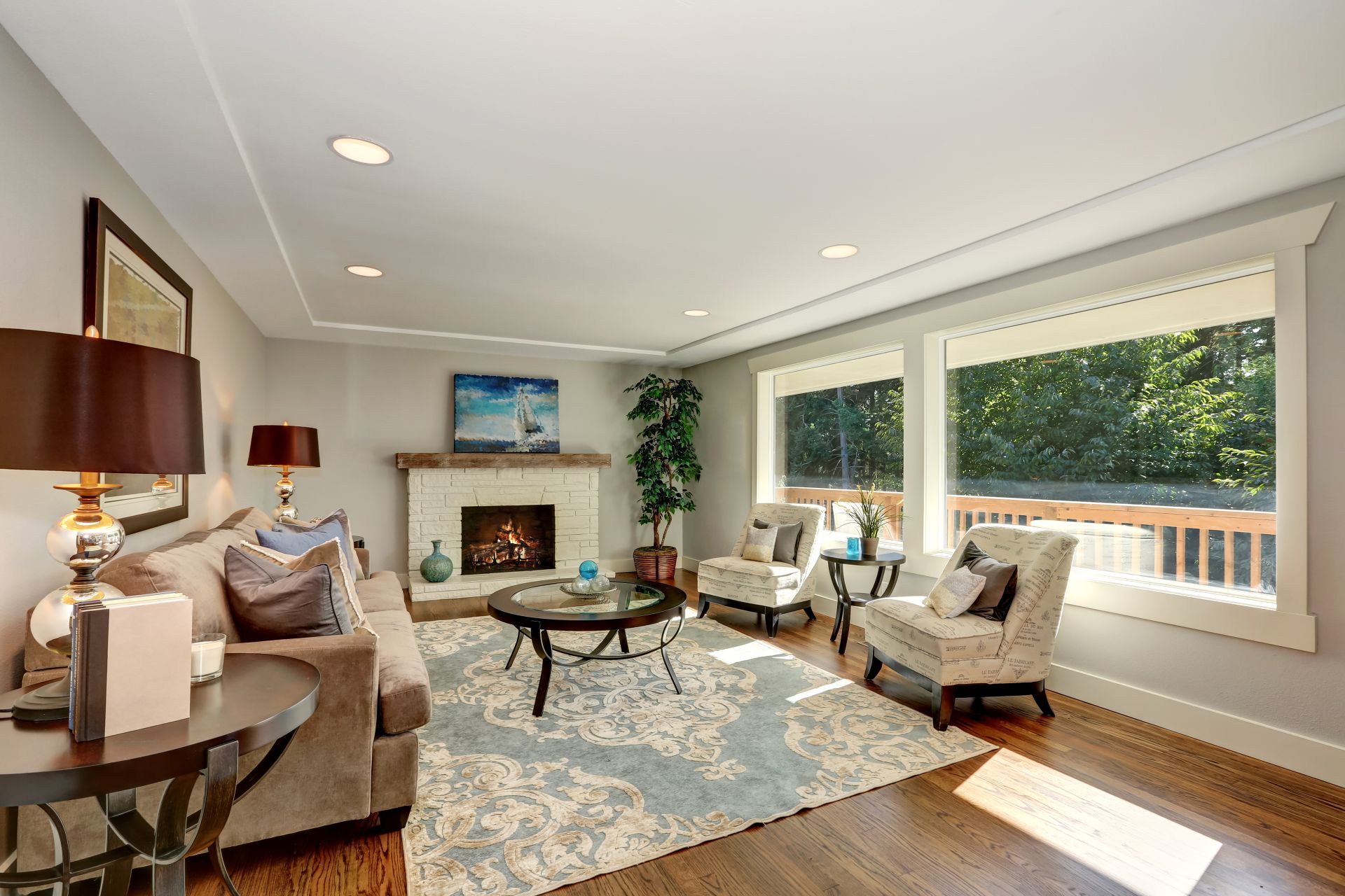 Cozy living room interior with hardwood floor and window view. Furnished with mocha colored sofa, vintage lounge Chairs and round glass top coffee table on a rug. Northwest, USA