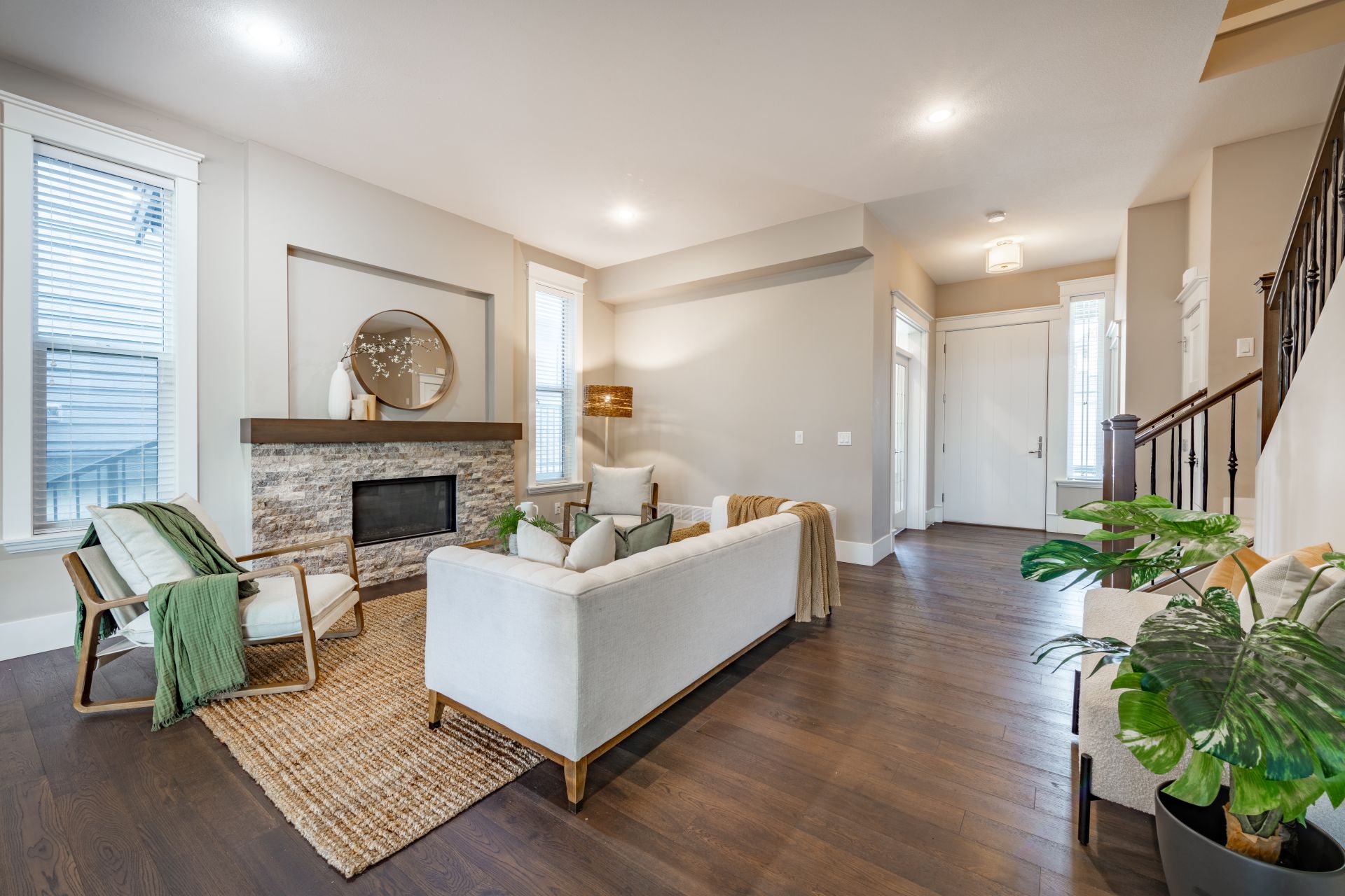 Simple living room interior with bohemian color tones moss green and beige hardwood floor staircase and a stone fireplace