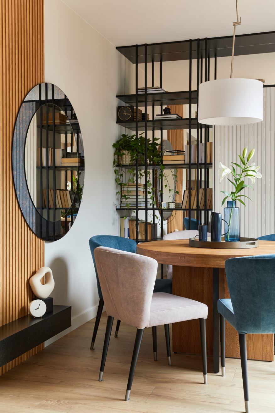 Stylish composition of elegant dining room interior design with velvet armchairs, design rounded wooden table and beautiful personal accessories. Glamour interior design inspiration. Template.