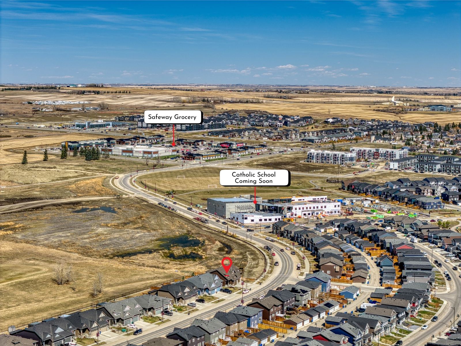 Aerial view of the D'Arcy area of Okotoks, Alberta, with a Safeway and a planned Catholic school labelled