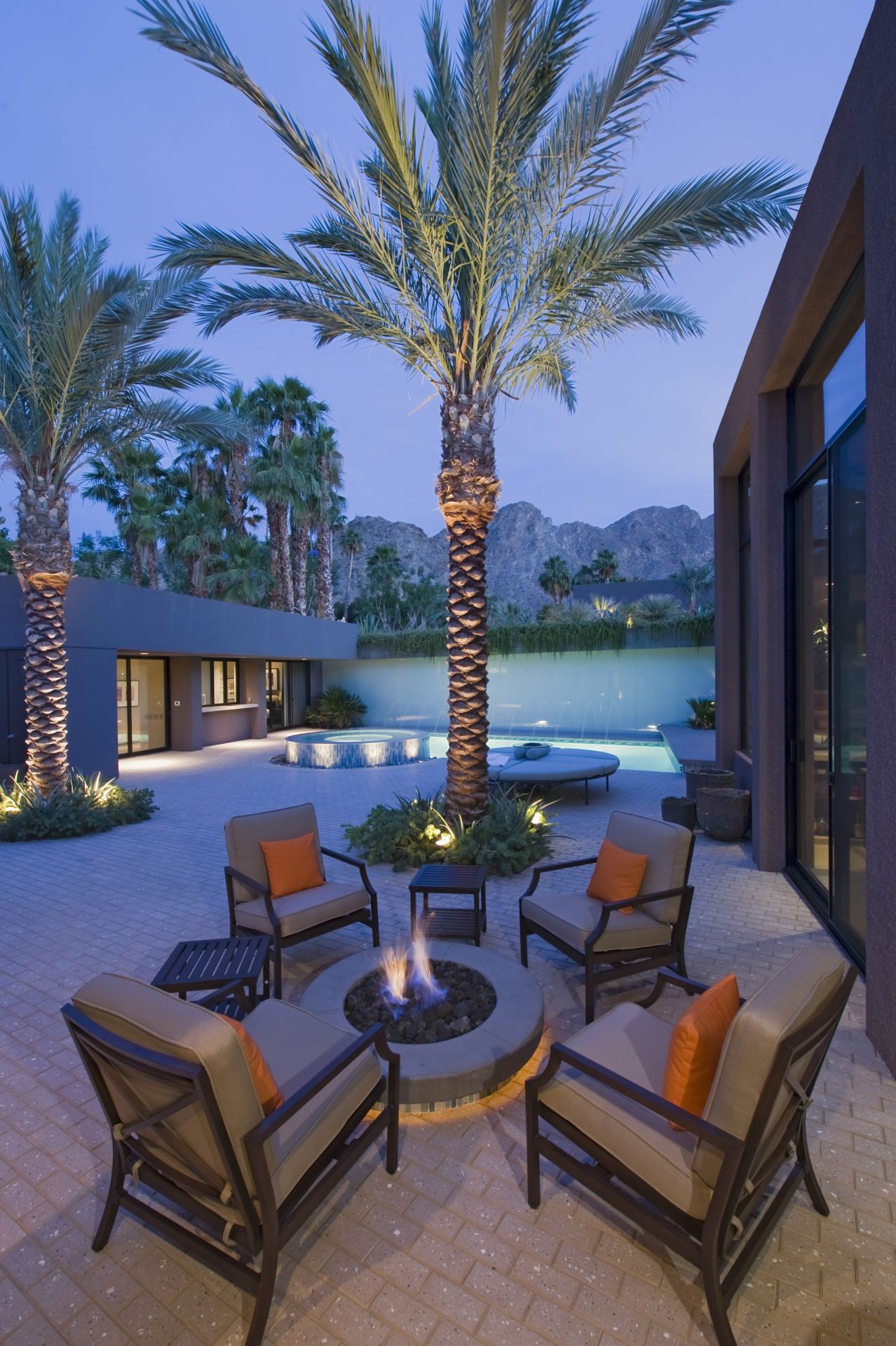 Burning fire pit surrounded by chairs on terrace of California home